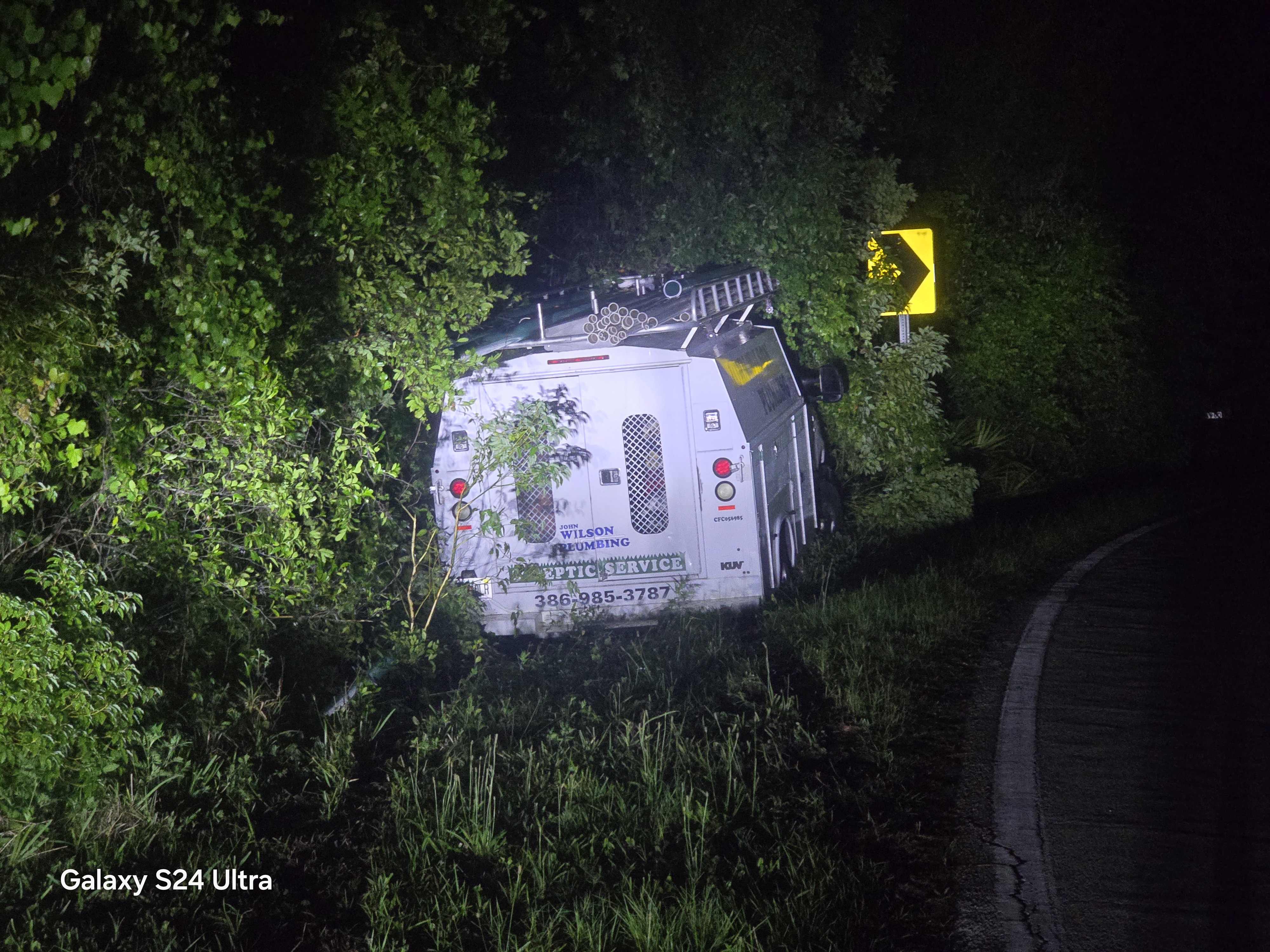 Service vehicle off road embedded in vegetation at curve
