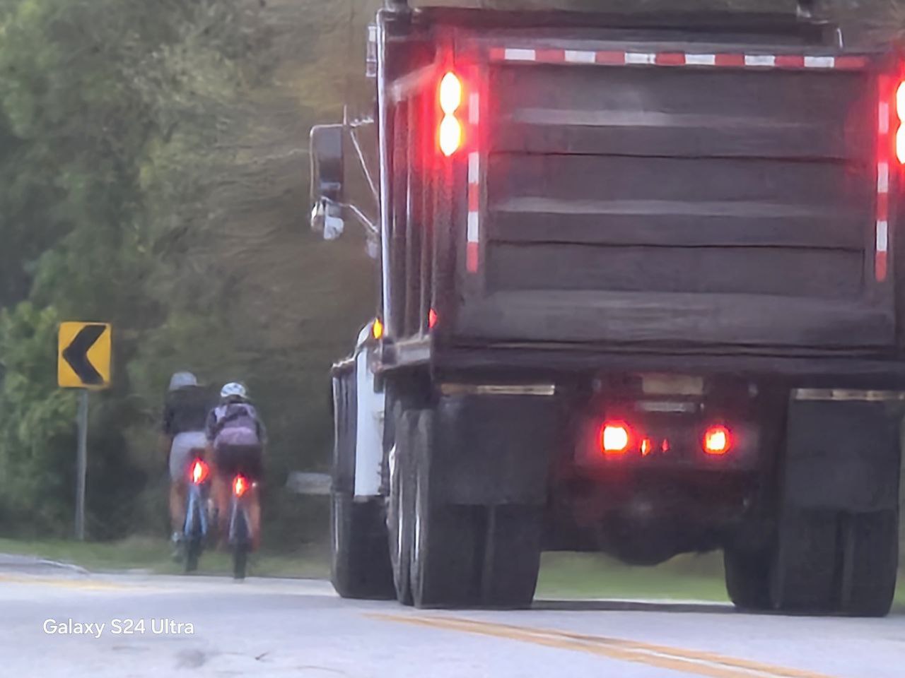 Dump truck following cyclists on curve with no shoulder
