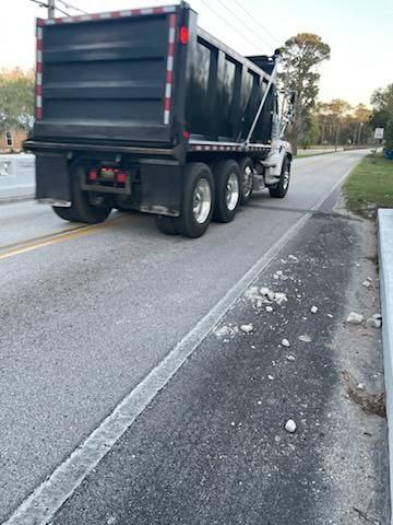 Dump truck riding center of bridge with rocks and debris on road