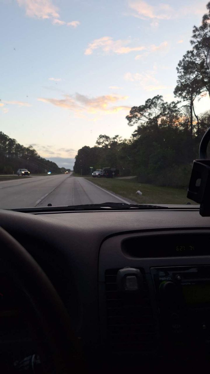 View from inside car approaching truck blocking US-92 and Old Daytona Rd curve at dusk